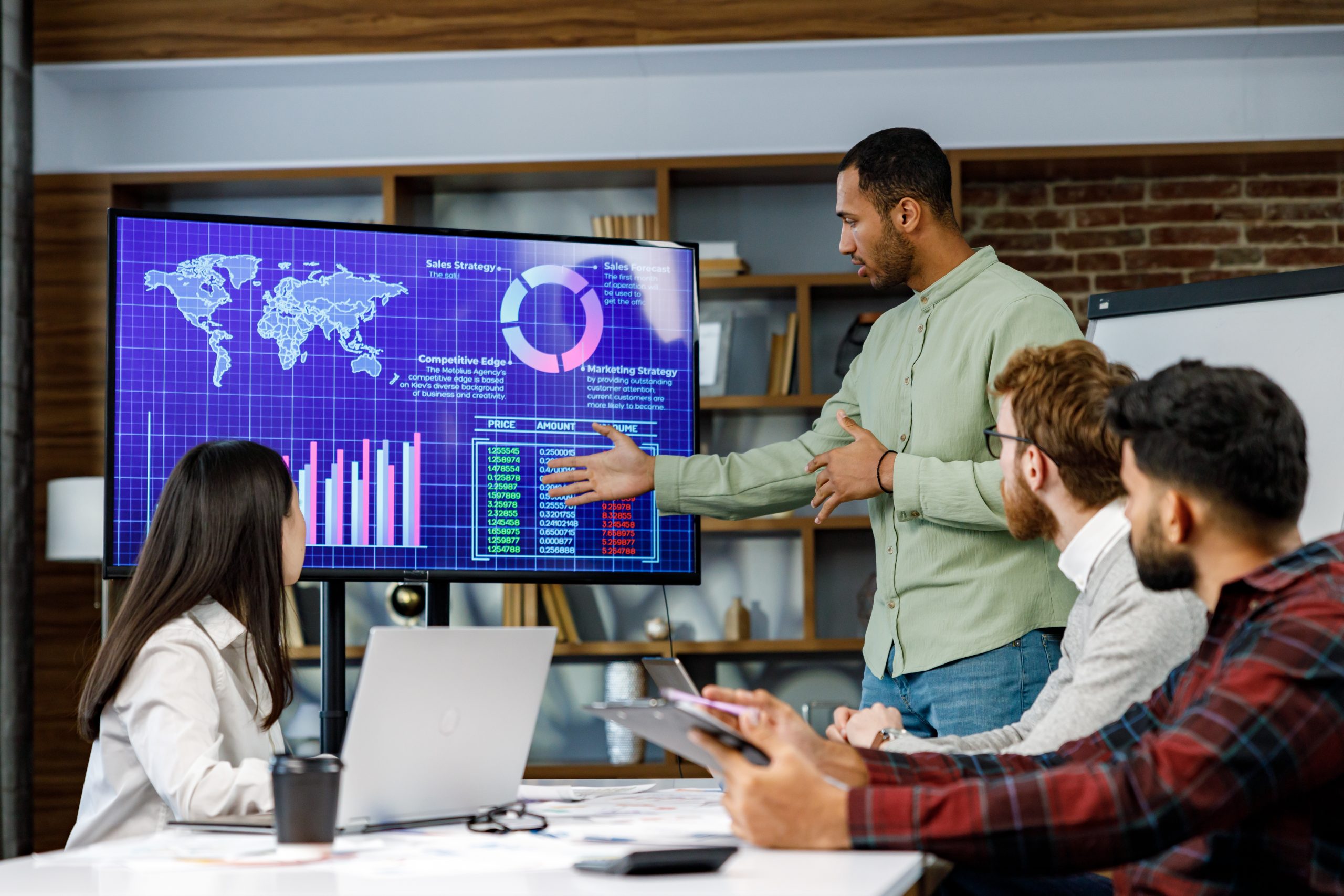 Motivated african american businessman having business meeting with managers, negotiating, using presentation tv with statistics, charts, big data. Digital entrepreneurs work on an e-commerce project.
