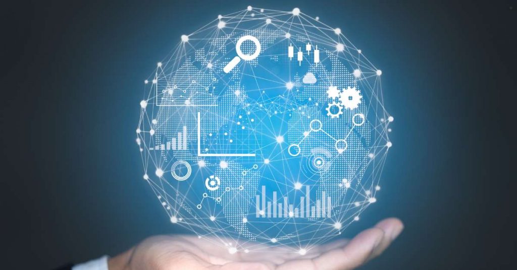 A hand holds up a glowing, blue-hued sphere, which is a stylized globe made of interconnected white lines. The globe is covered with various icons and charts representing data analytics, including bar graphs, line graphs, magnifying glasses, and cogs.
